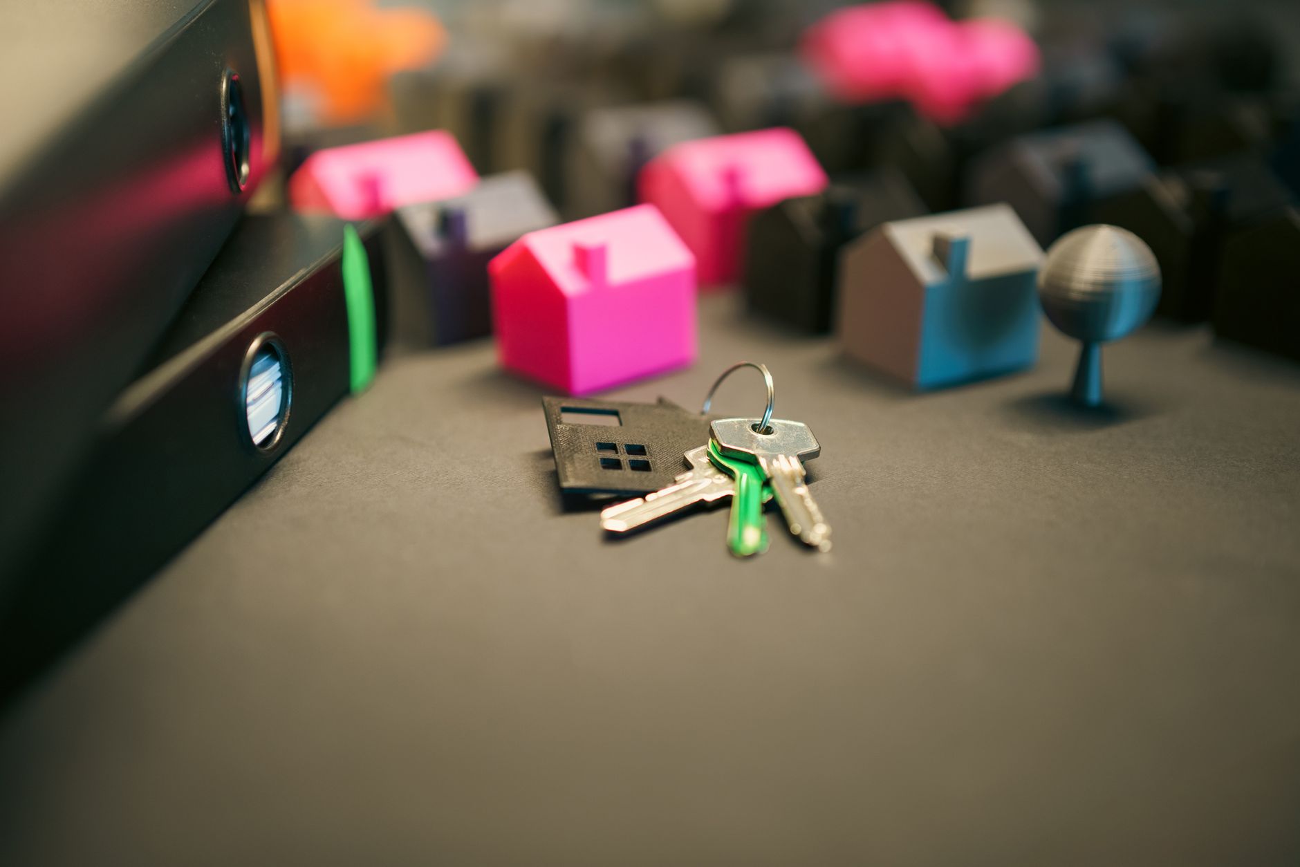 Miniature model houses and keys on a desk, symbolizing real estate and property investment.