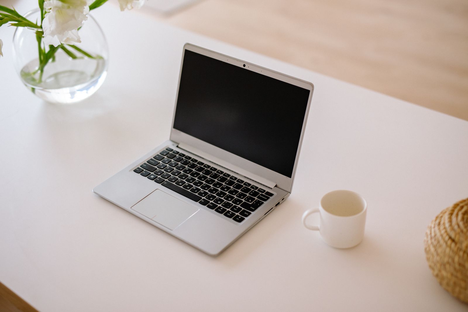 A bright minimalist workspace with an open laptop, coffee mug, and a vase — the kind of setup a workflow keeps running while you work